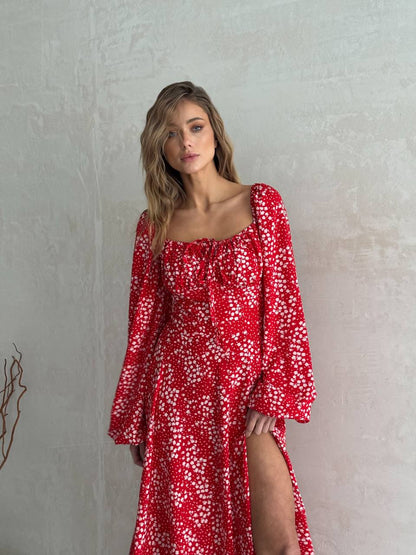 Woman wearing a red floral dress against a plain background