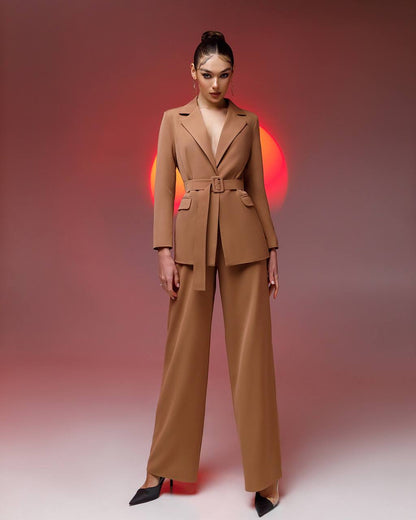 Woman wearing a brown suit against a gradient background