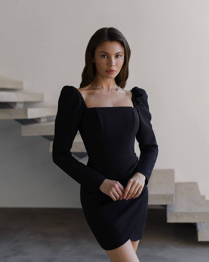 Woman wearing a black dress with puffed sleeves in an indoor setting