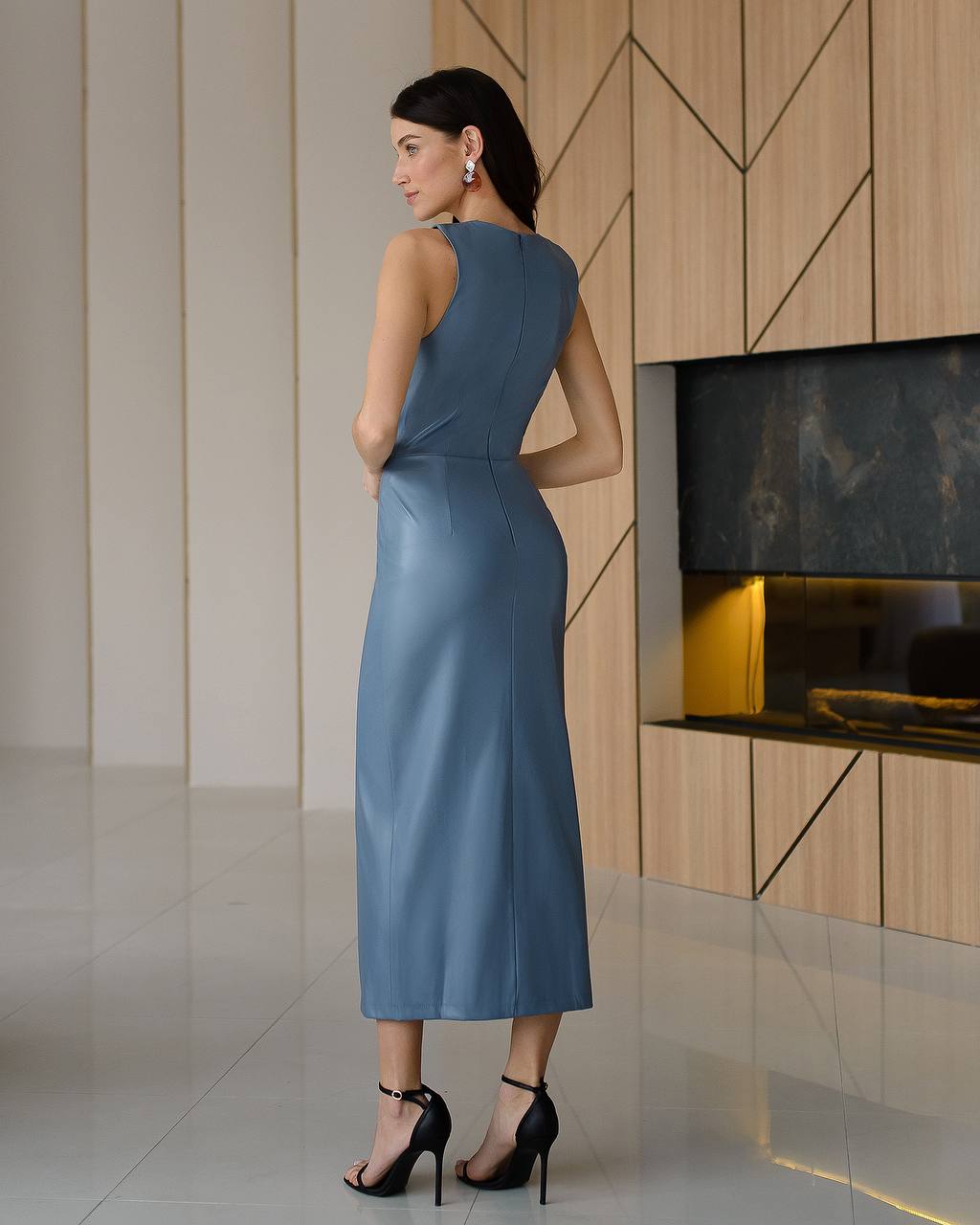 Woman in a blue dress standing in a modern interior setting.