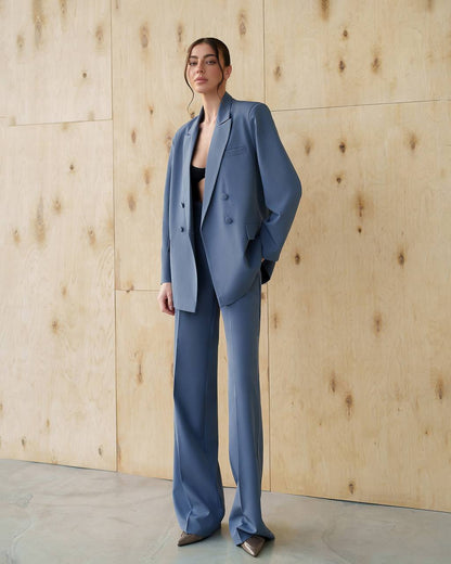 Woman wearing a blue suit standing against a wooden wall.