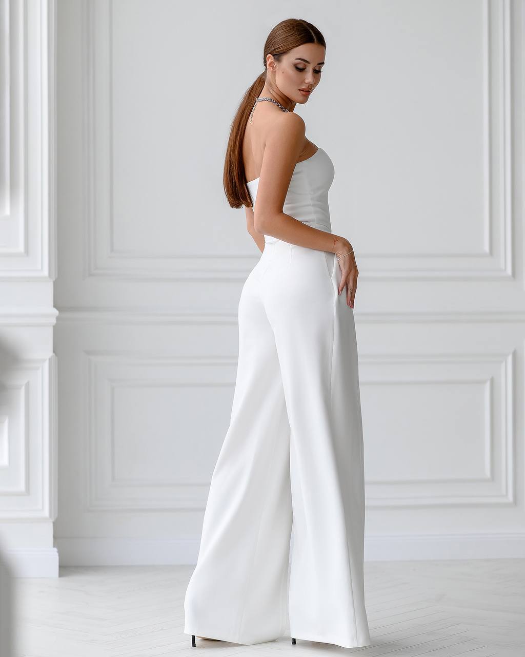 Woman wearing a white strapless jumpsuit in a minimalistic setting
