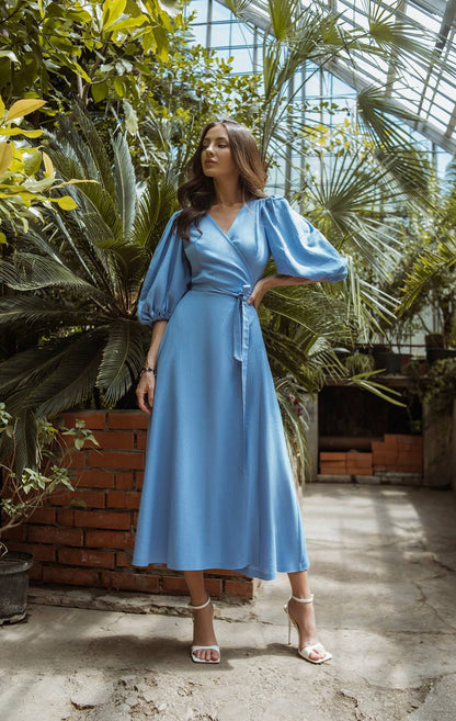 Woman in a blue dress standing in a greenhouse with plants around