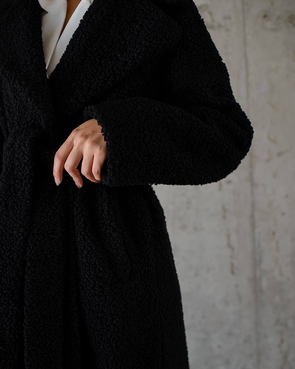 Person wearing a black coat with a neutral background