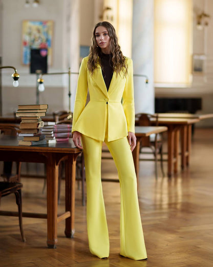 Woman in a bright yellow suit standing in a room with wooden tables and chairs.