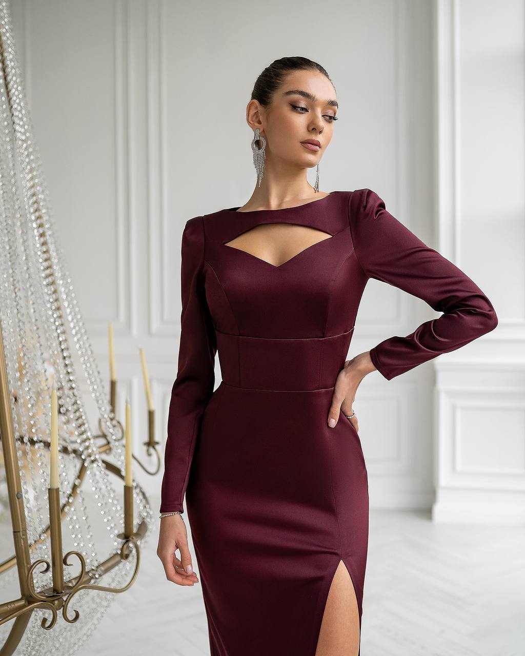 Woman wearing a burgundy dress with cut-out design in an elegant room.