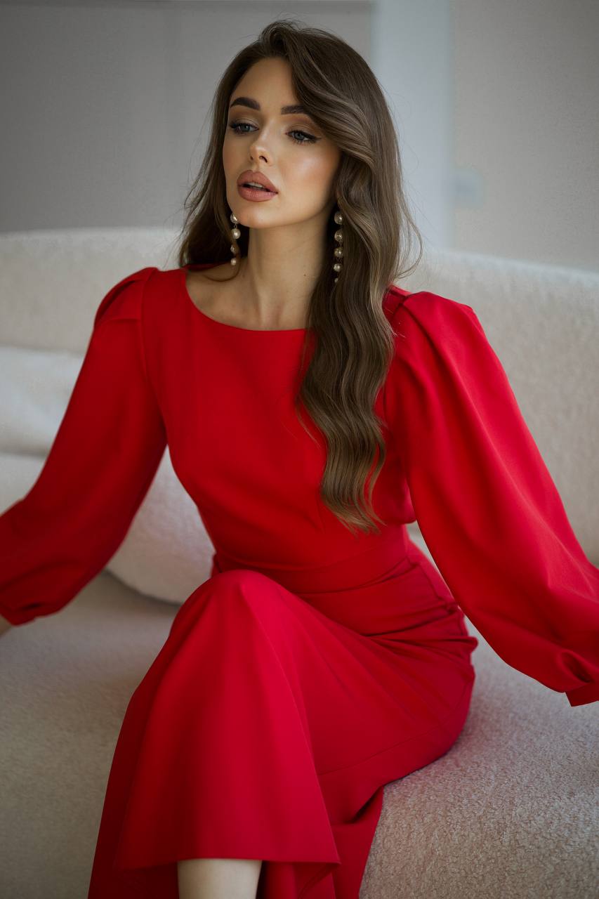 Woman wearing a red dress sitting on a light-colored couch.