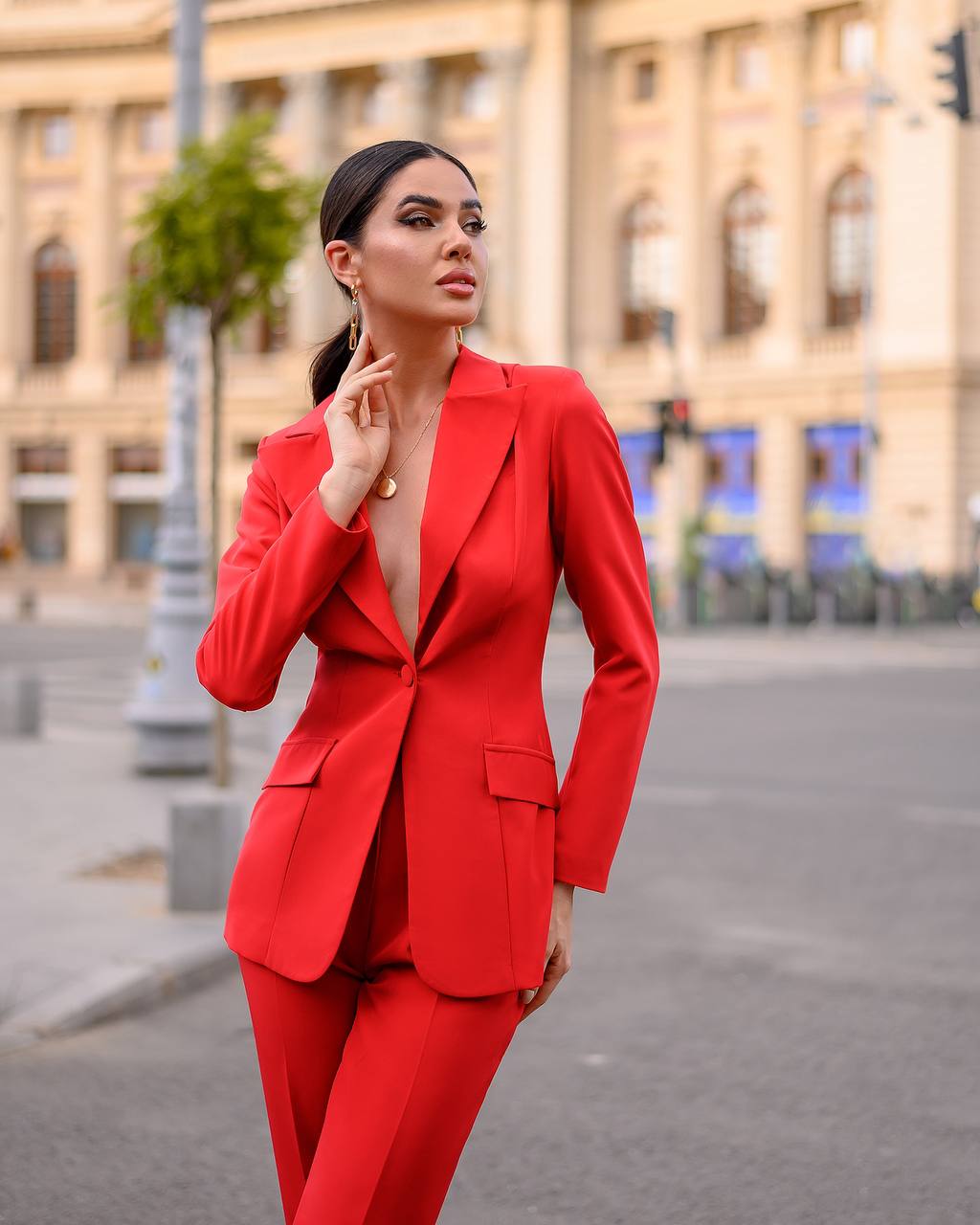 Woman in a red suit standing on a city street