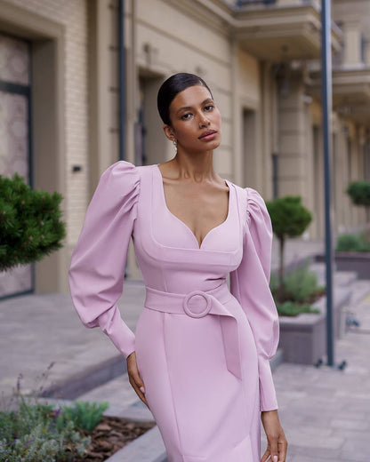 Woman wearing a pink dress with puffed sleeves in an urban setting