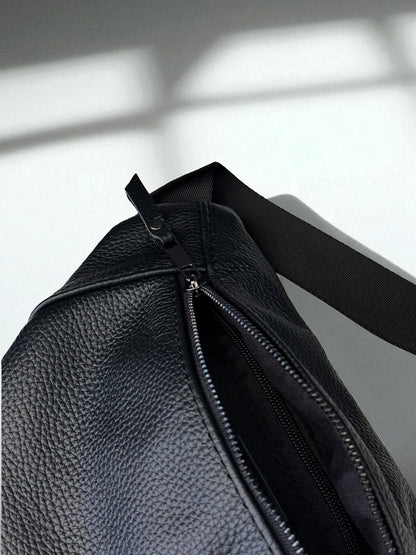 Close-up of a black pebbled leather bag with a partially unzipped zipper and a black shoulder strap, set against a light gray background with soft window shadow patterns.