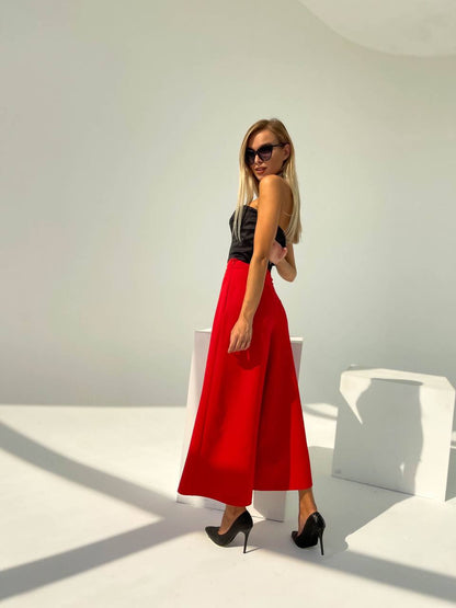 Woman wearing a black top and red skirt in a minimalistic setting