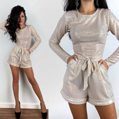 Woman wearing a beige lace romper with long sleeves against a white background