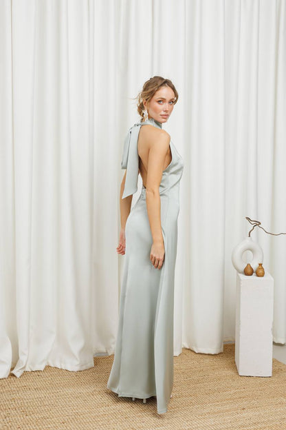 Woman in a light gray dress standing in front of white curtains
