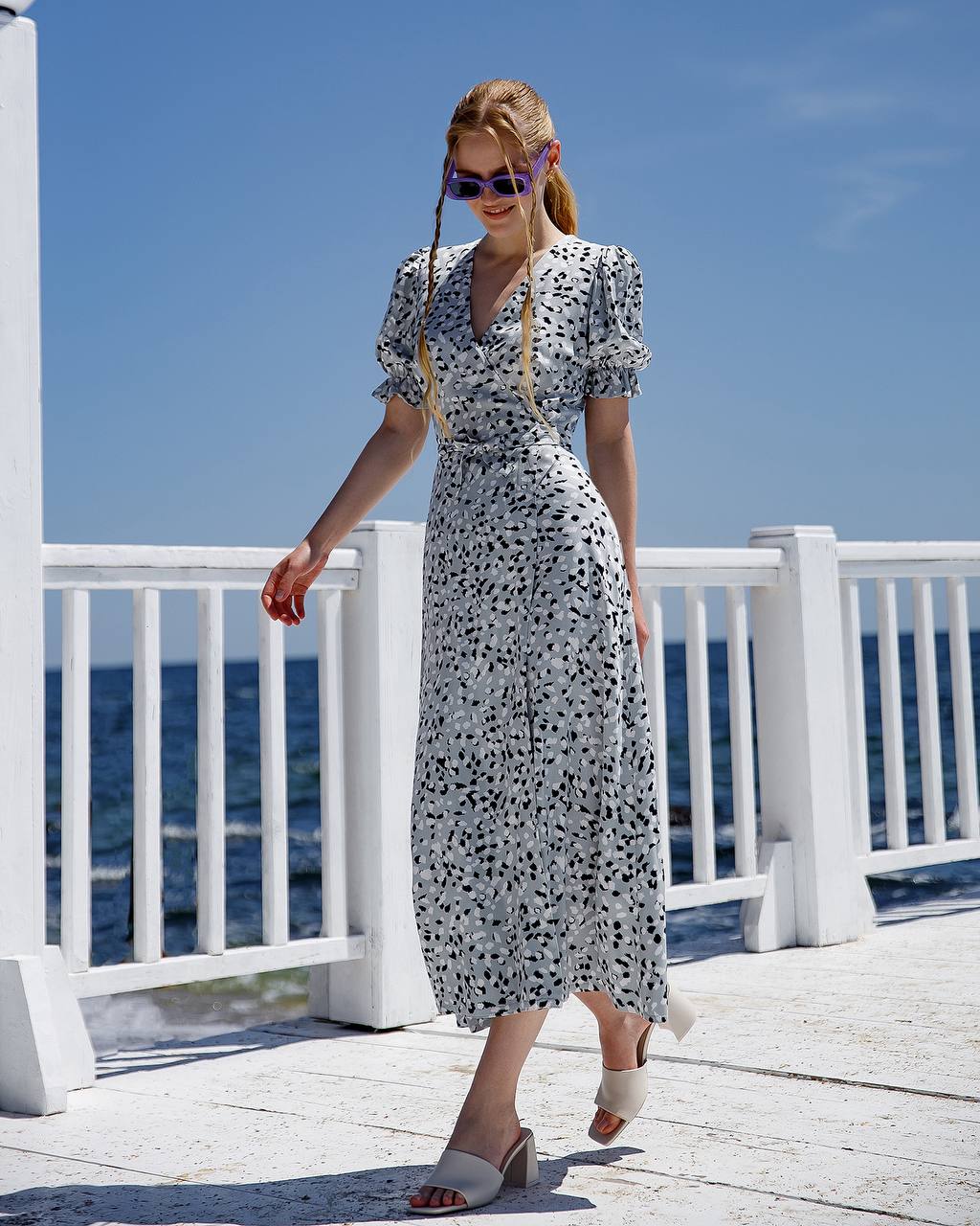 Woman in a floral dress standing on a white deck with ocean view