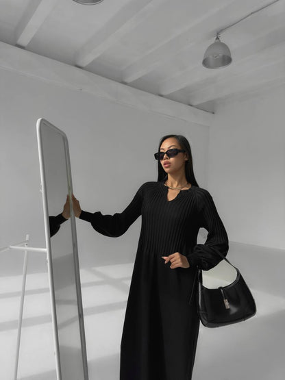 Woman in a black outfit holding a mirror in a minimalistic setting