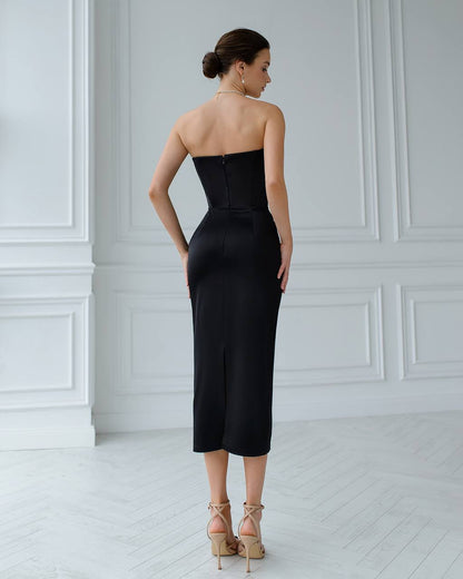 Woman wearing a black strapless dress in a white room