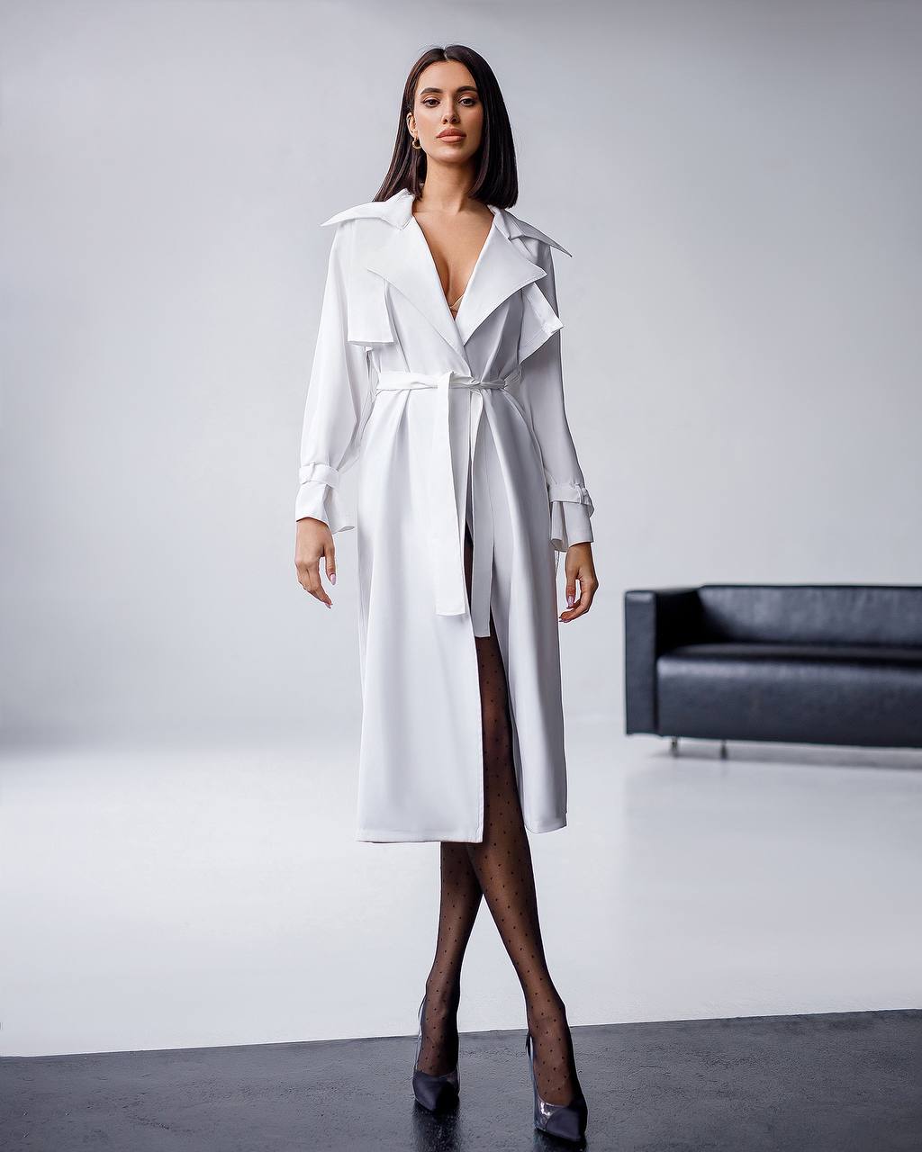 Woman wearing a white trench coat in a minimalistic setting