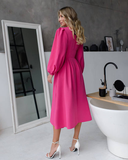 Woman in a bright pink dress standing in a modern bathroom.