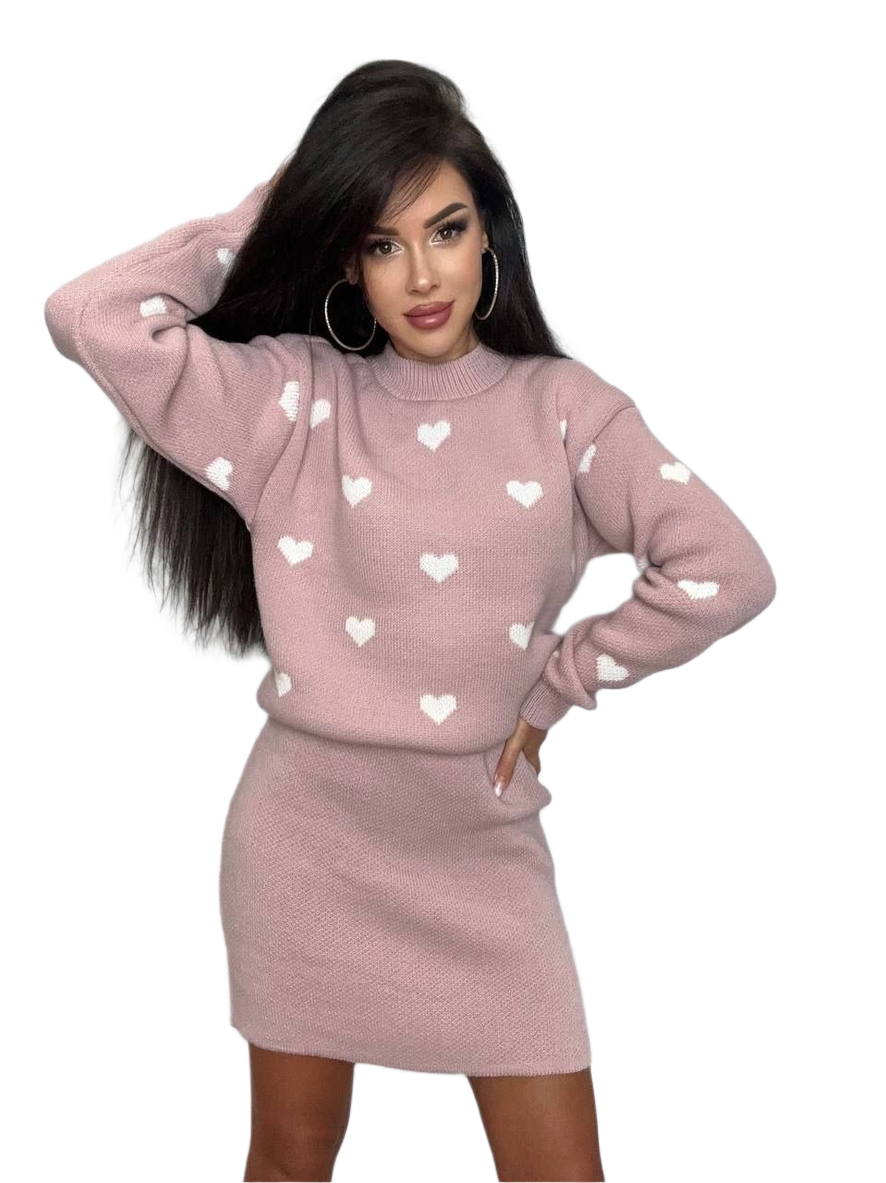 Woman wearing a pink sweater with heart patterns and a matching skirt on a white background
