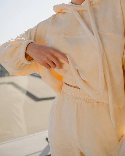 Person wearing a light yellow hoodie and pants with a blurred background
