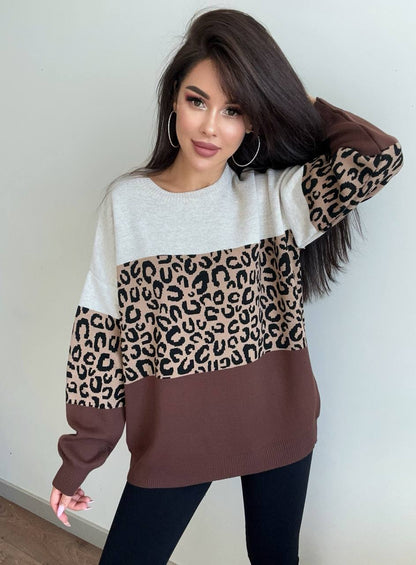 Woman wearing a sweater with leopard print sleeves against a plain background
