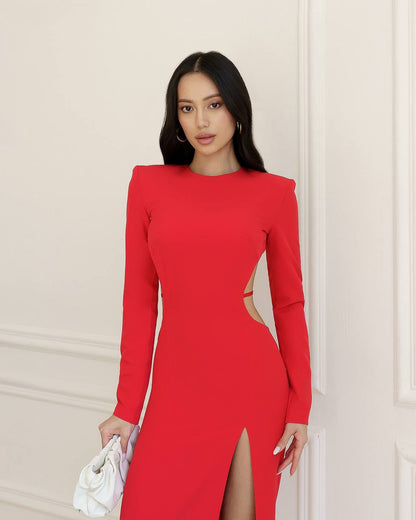 Woman wearing a red dress with cut-out design against a beige wall.