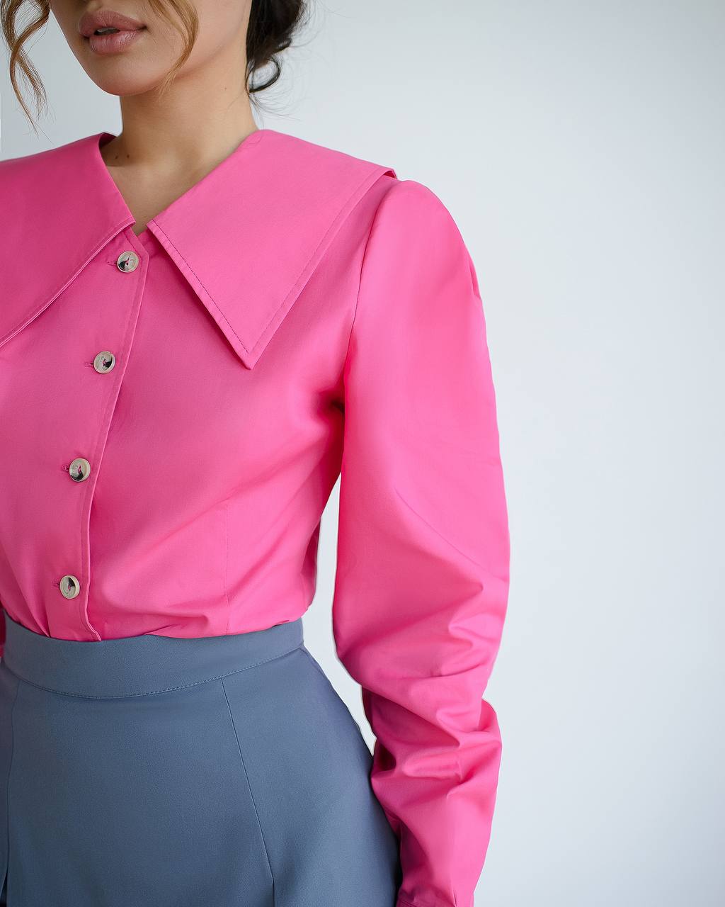 Person wearing a bright pink blouse with a white background