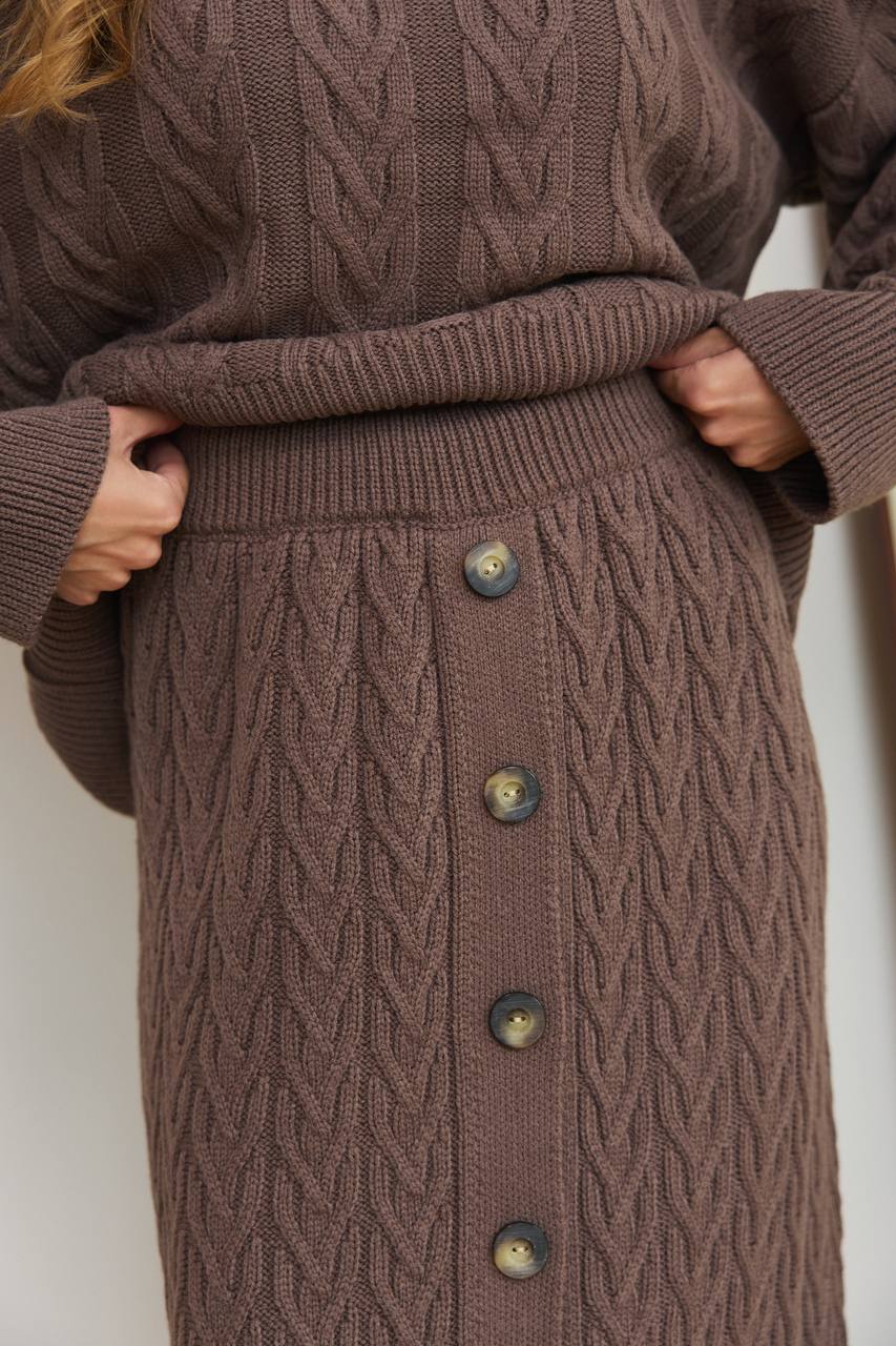 Brown knitted dress with button details on a plain background