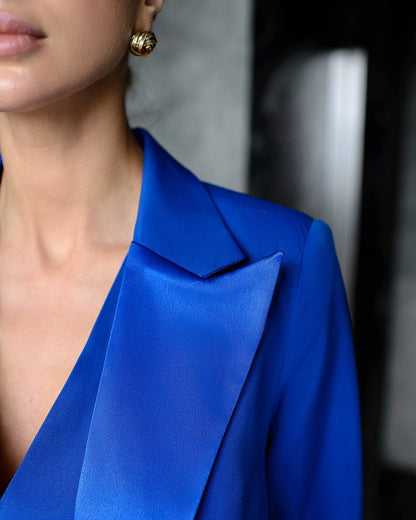 Close-up of a person wearing a blue blazer with a blurred background