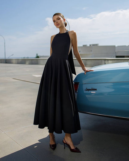 Woman in a black dress standing next to a blue car on a rooftop.
