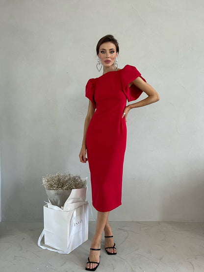 Woman wearing a red dress with puffed sleeves against a plain background