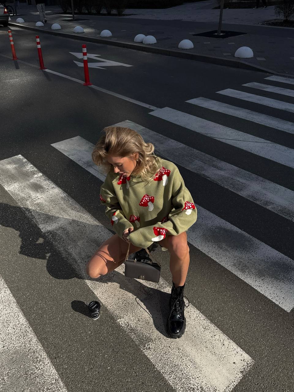 Person wearing a green sweater with red patterns on a crosswalk