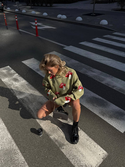 Person wearing a green sweater with red patterns on a crosswalk