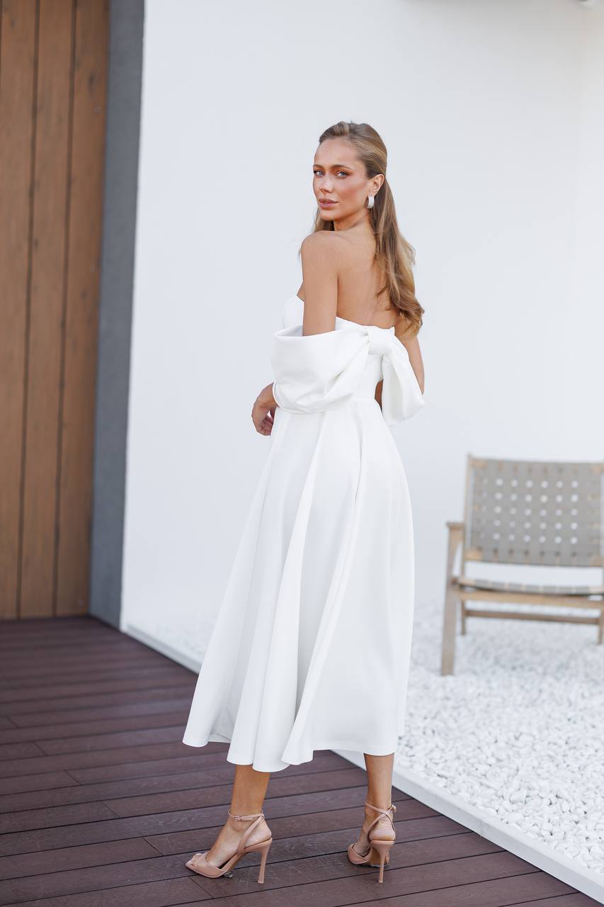 Woman in a white dress standing in a modern indoor setting.