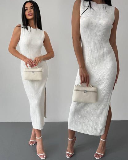 Woman wearing a white ribbed dress holding a small handbag on a gray background