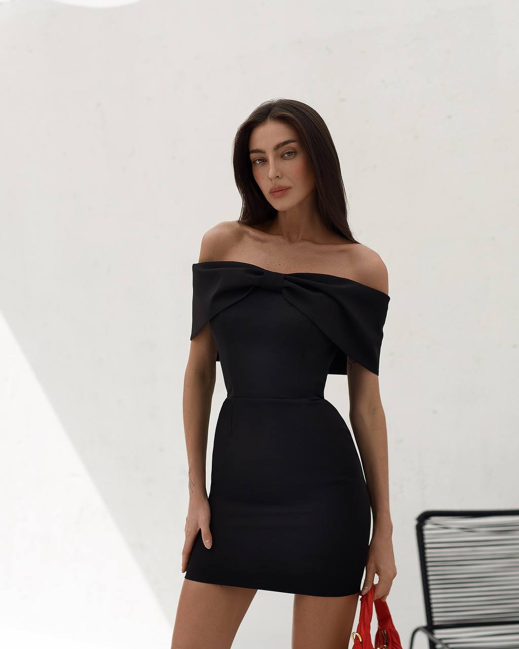 Woman wearing a black off-shoulder dress against a white background