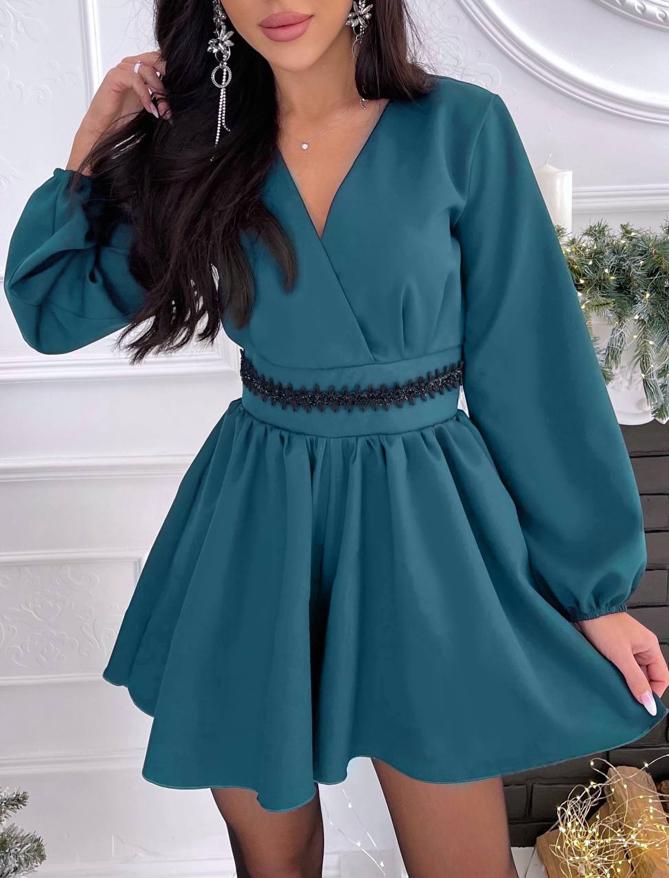 Teal dress with long sleeves and lace detail on a white background