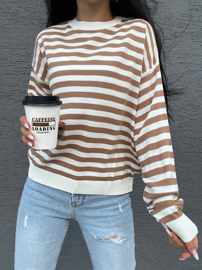 Person wearing a brown and white striped sweater holding a coffee cup with 'Caffeine Loading' text.