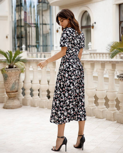 Woman in a floral dress standing in an elegant outdoor setting.