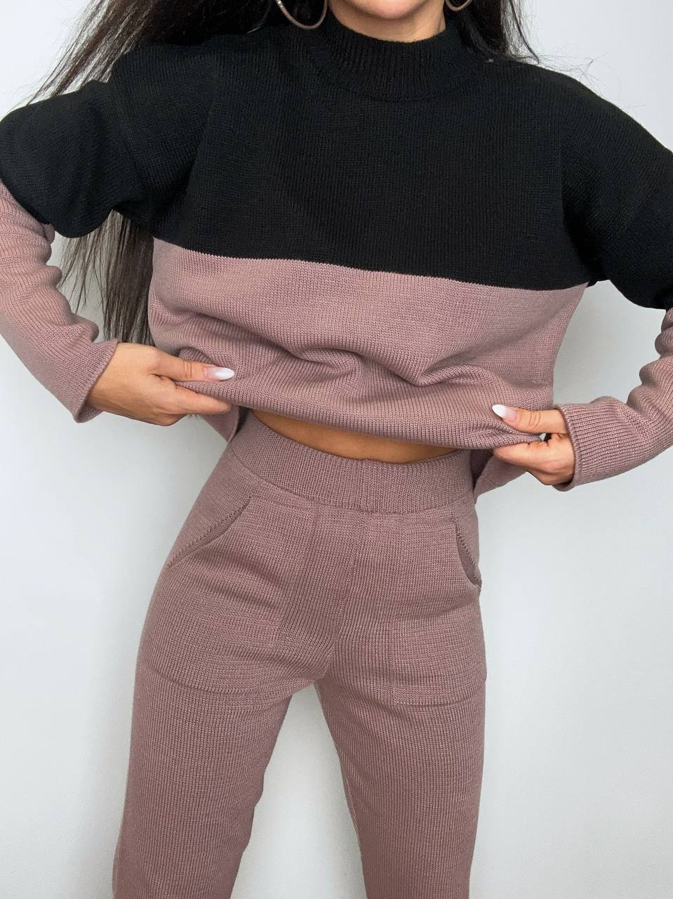 Two-tone sweater and pants set with black and pink colors on a plain background