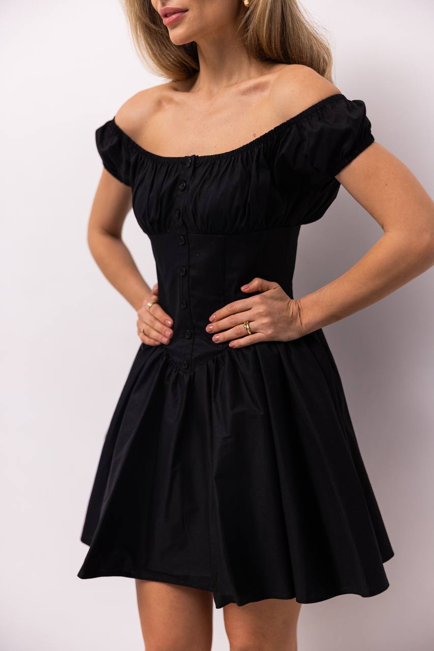 Black off-shoulder dress worn by a model against a white background