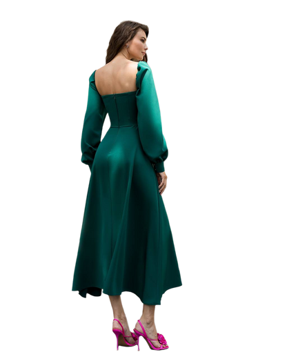 Woman wearing a green dress with a fitted bodice and flared skirt on a white background