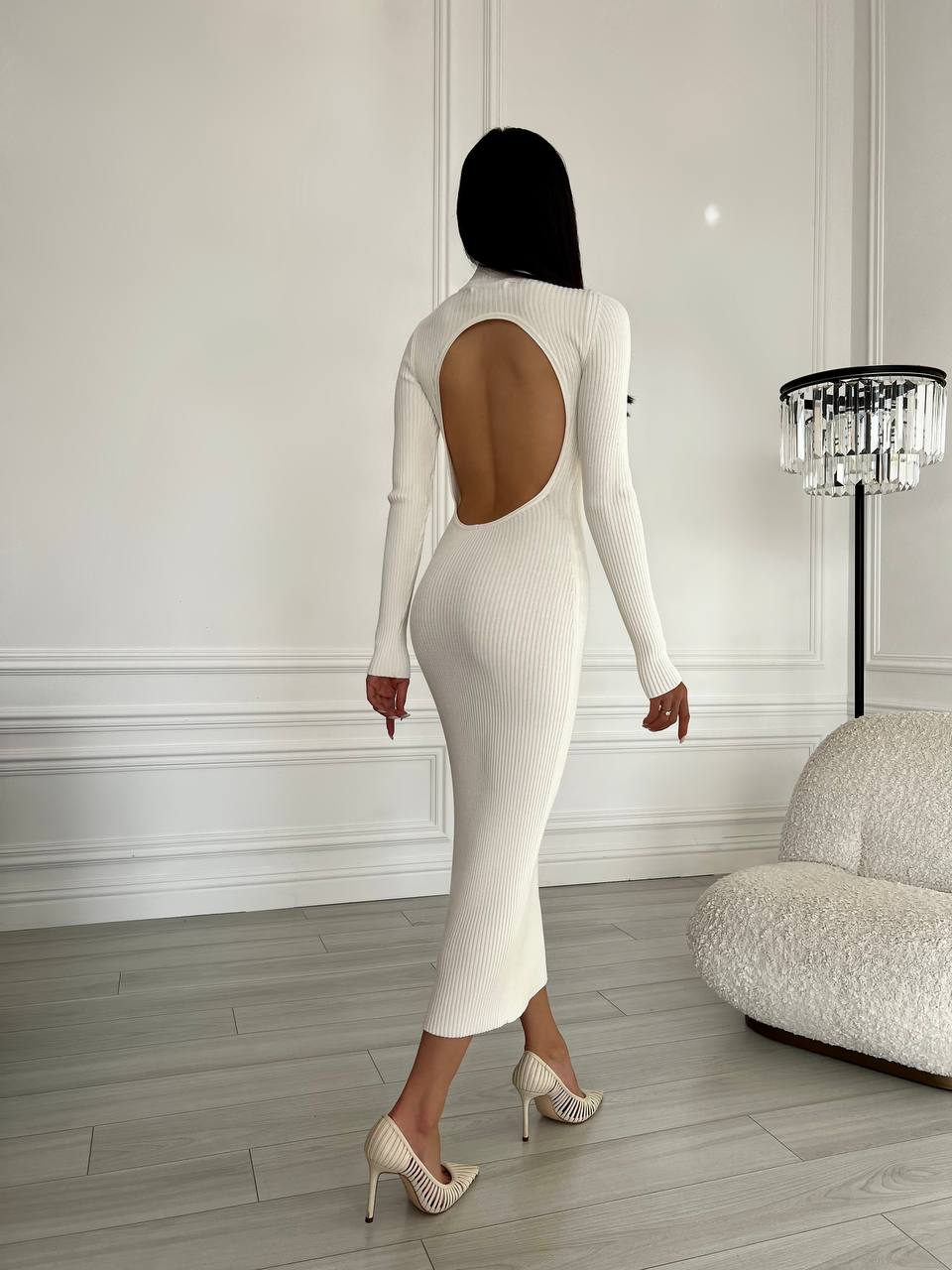Person wearing a white dress with a cutout back in an elegant room.