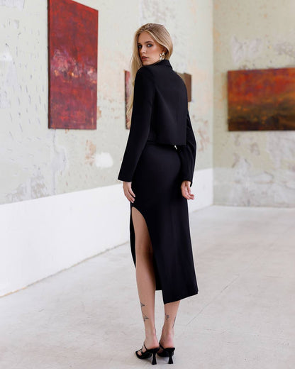 Woman in a black outfit standing in an art gallery with abstract paintings on the wall.