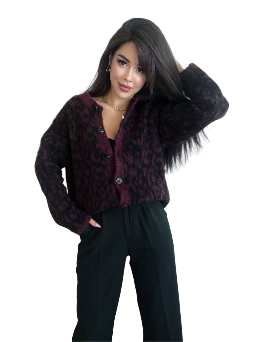 Woman wearing a dark patterned cardigan over a black top with black pants on a white background