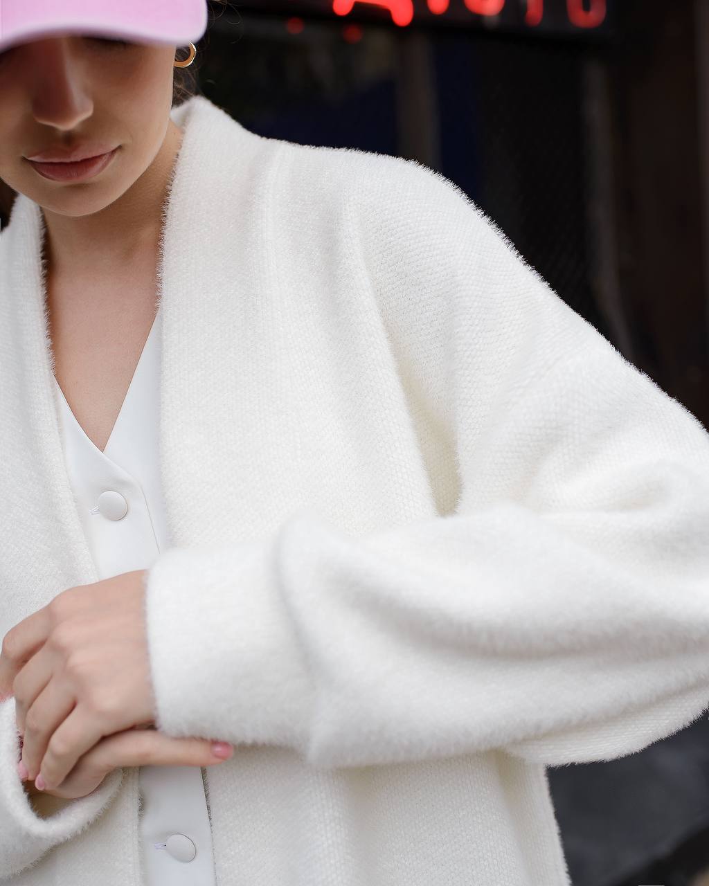 Person wearing a white cardigan with a blurred background