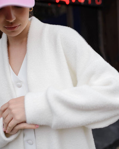 Person wearing a white cardigan with a blurred background