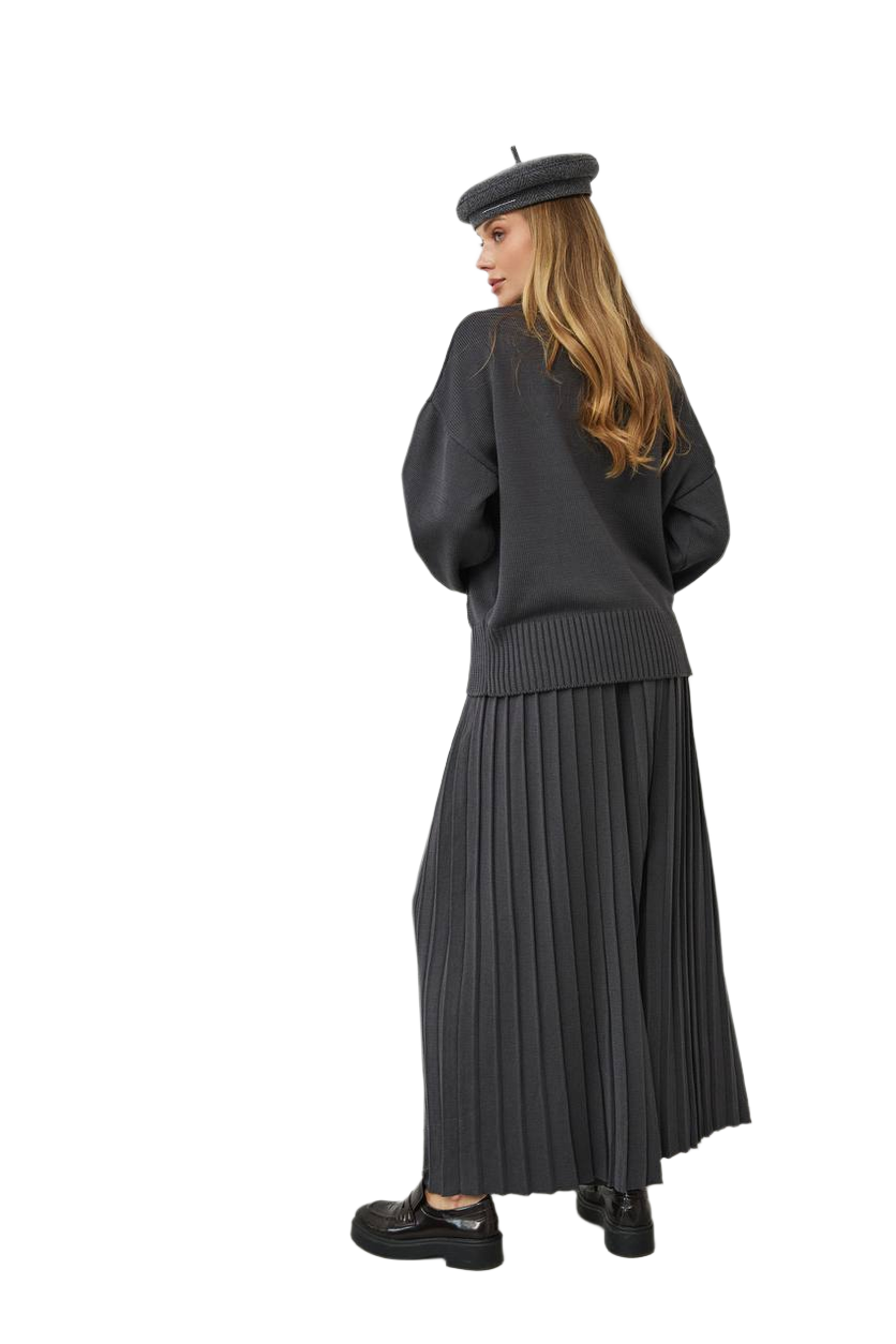 Person wearing a black outfit with a pleated skirt and beret on a white background