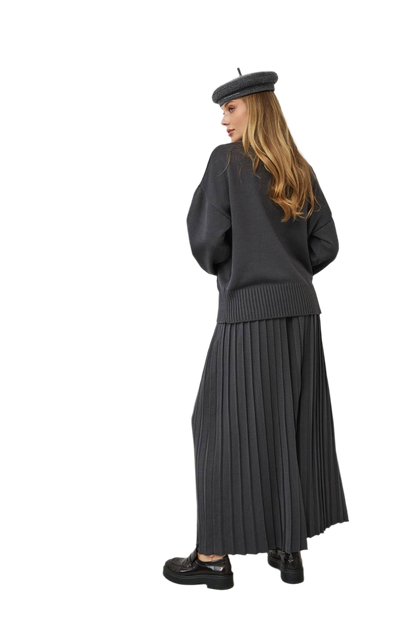 Person wearing a black outfit with a pleated skirt and beret on a white background