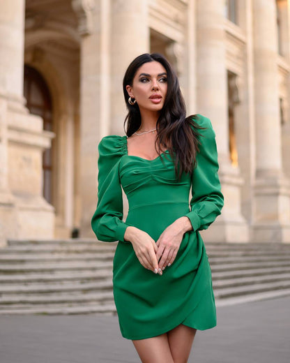 Woman in a green dress standing in front of classical architecture